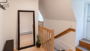 Eine Treppe mit Holzwertlauf und ein in einem schwarzen Rahmen gefasster Spiegel, der an der Wand lehnt.