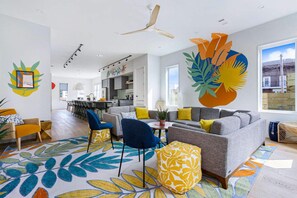 A modern living room with a grey sofa, blue chairs, yellow cushions, and a colorful patterned rug.