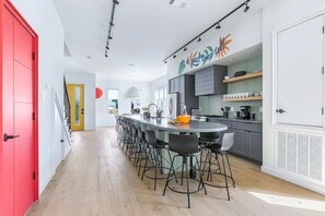 A modern kitchen with a long island, bar stools, and a red door.