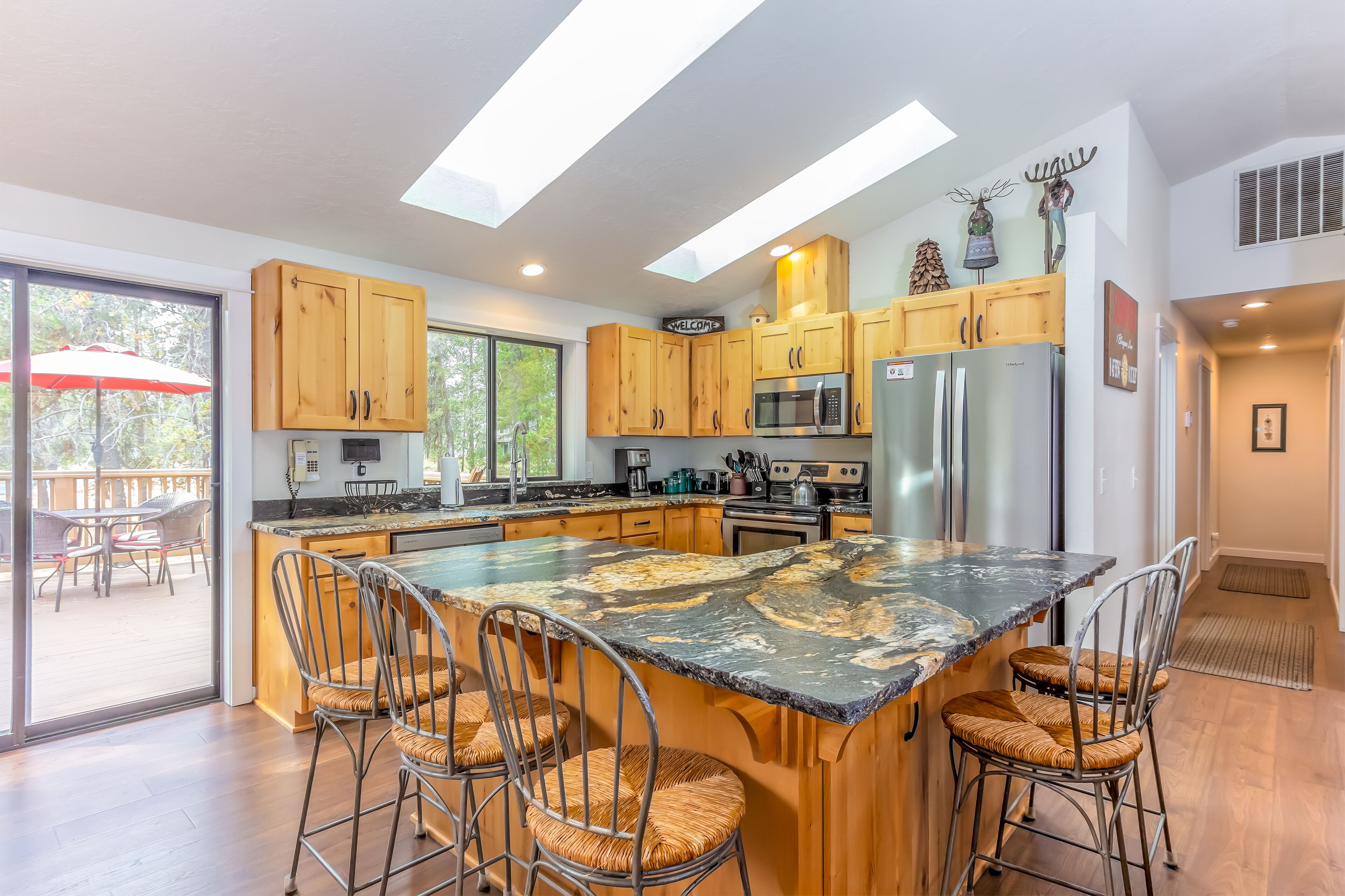 Una cucina moderna con mobili in legno, una grande isola con sgabelli da bar, elettrodomestici in acciaio inossidabile e un lucernario.
