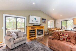 A spacious living room with a fireplace, a dining area, and large windows.