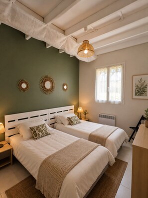 Une chambre avec deux lits, un luminaire suspendu et une fenêtre avec des rideaux.