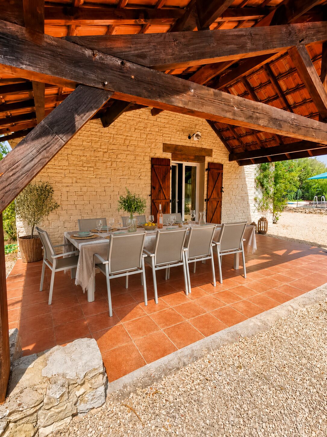 Une terrasse extérieure avec un mur en briques, des poutres en bois et une table dressée pour le repas.