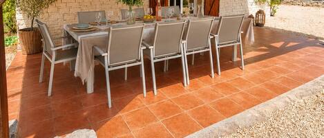 An outdoor patio with a brick wall, wooden beams, and a table set for dining.