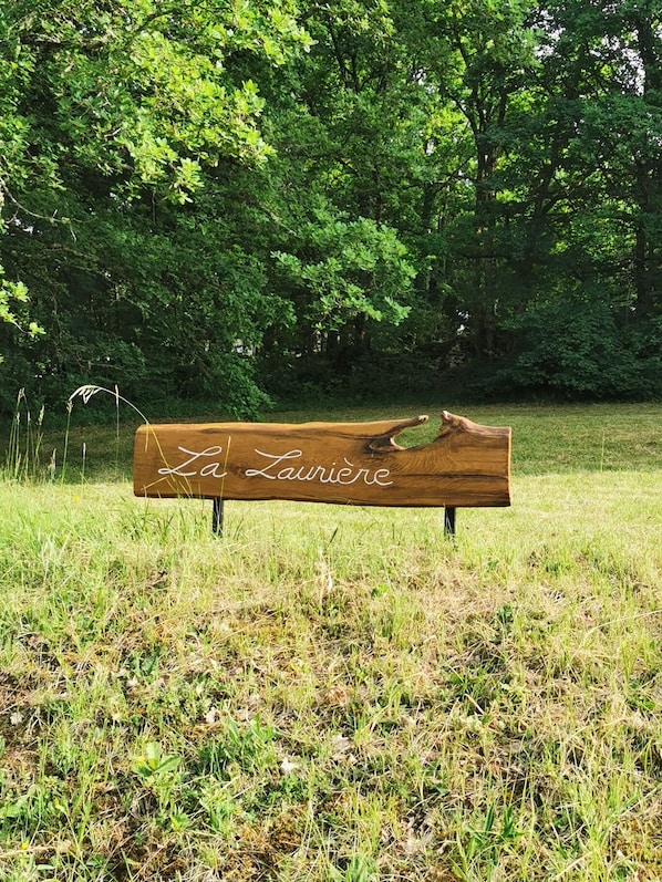 A wooden bench with the inscription "La Laniere" in a grassy field with trees in the background.