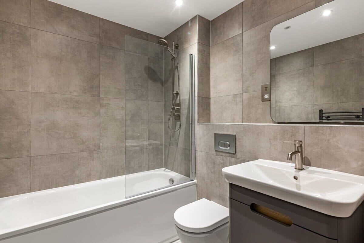 A modern bathroom with a bathtub, toilet, and sink.