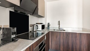A modern kitchen with a black countertop, stainless steel appliances, and wooden cabinets. - Stay Zeni – Contemporary 2 BR Flat in York, Ouse Court (York)