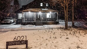 Ein mit Schnee bedecktes Haus mit einem Schild, auf dem '6021 SENTINEL RD' steht.