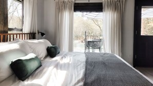 Ein Schlafzimmer mit Bett, Fenster und Blick ins Freie.