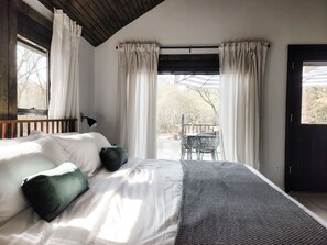A bedroom with a bed, a window, and a view of the outdoors.