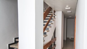 Een modern interieur met een houten trap, witte muren en een betegelde vloer.