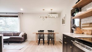 Una cocina moderna con comedor, suelo de madera y un ventanal grande.