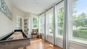 Una habitación con mesa de fútbol, una silla y ventanas amplias que dan a zonas verdes.