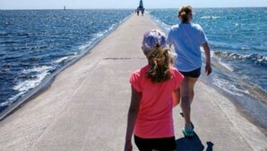 Un muelle de hormigón que se adentra en el mar, con gente caminando sobre él.