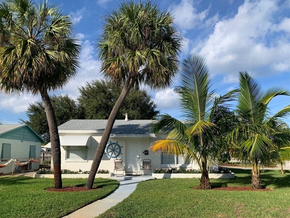 A house with a white exterior, a blue door, and a wheel-like decoration on the front.