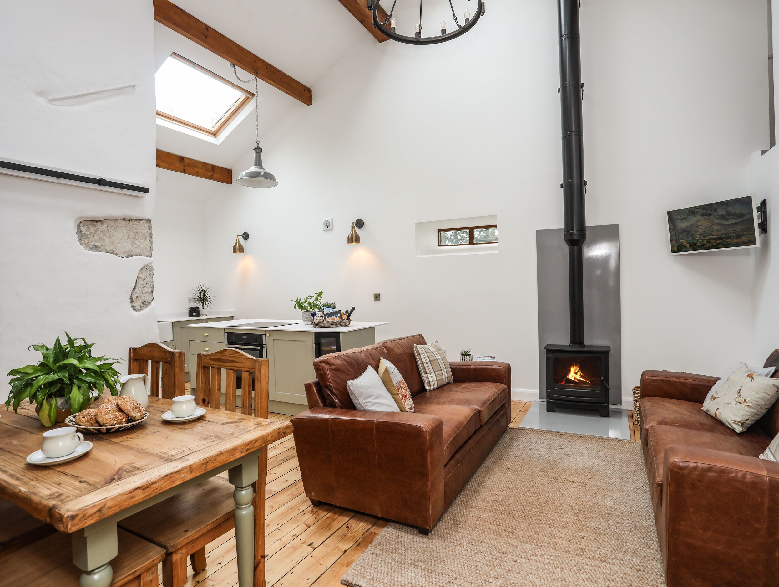 A cozy living room with a fireplace, a dining area with a wooden table, and a kitchen with a window.