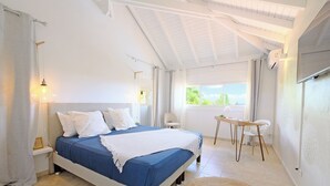 A bedroom with a bed, bedside tables, a desk, and a view of the outdoors.