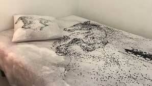 Een bed met een beddengoed met een patroon en een kussen met een zwart ontwerp.