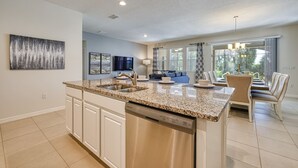A modern kitchen with a central island, built-in dishwasher, and a dining area with a table and chairs.