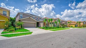 A residential street with modern houses, a clear sky, and well-maintained lawns.