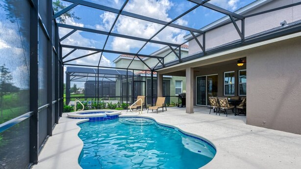 A swimming pool with a glass enclosure, surrounded by lounge chairs and a patio area.