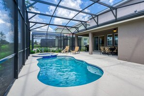 A swimming pool with a glass enclosure, surrounded by lounge chairs and a patio area. - Solterra Resort villa 6 Bedrooms Pool spa Disney  Family Vacation Offer (davenport)