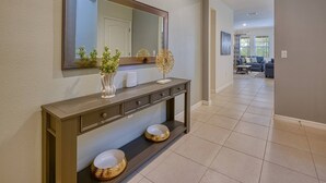 A modern bathroom with a large mirror, a console table with decorative items, and a tiled floor.