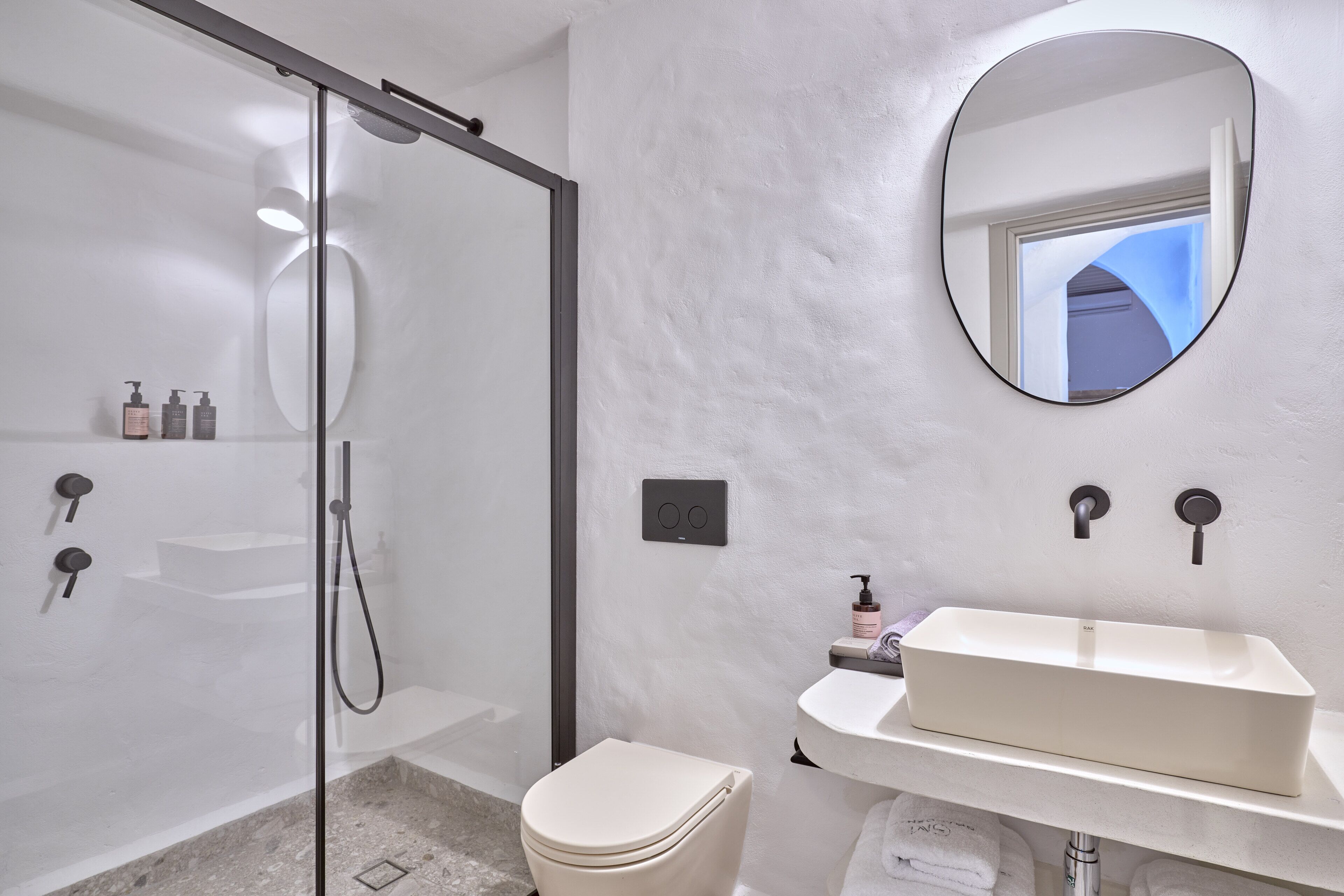 A modern bathroom with a glass-enclosed shower, a white sink, and a large mirror.