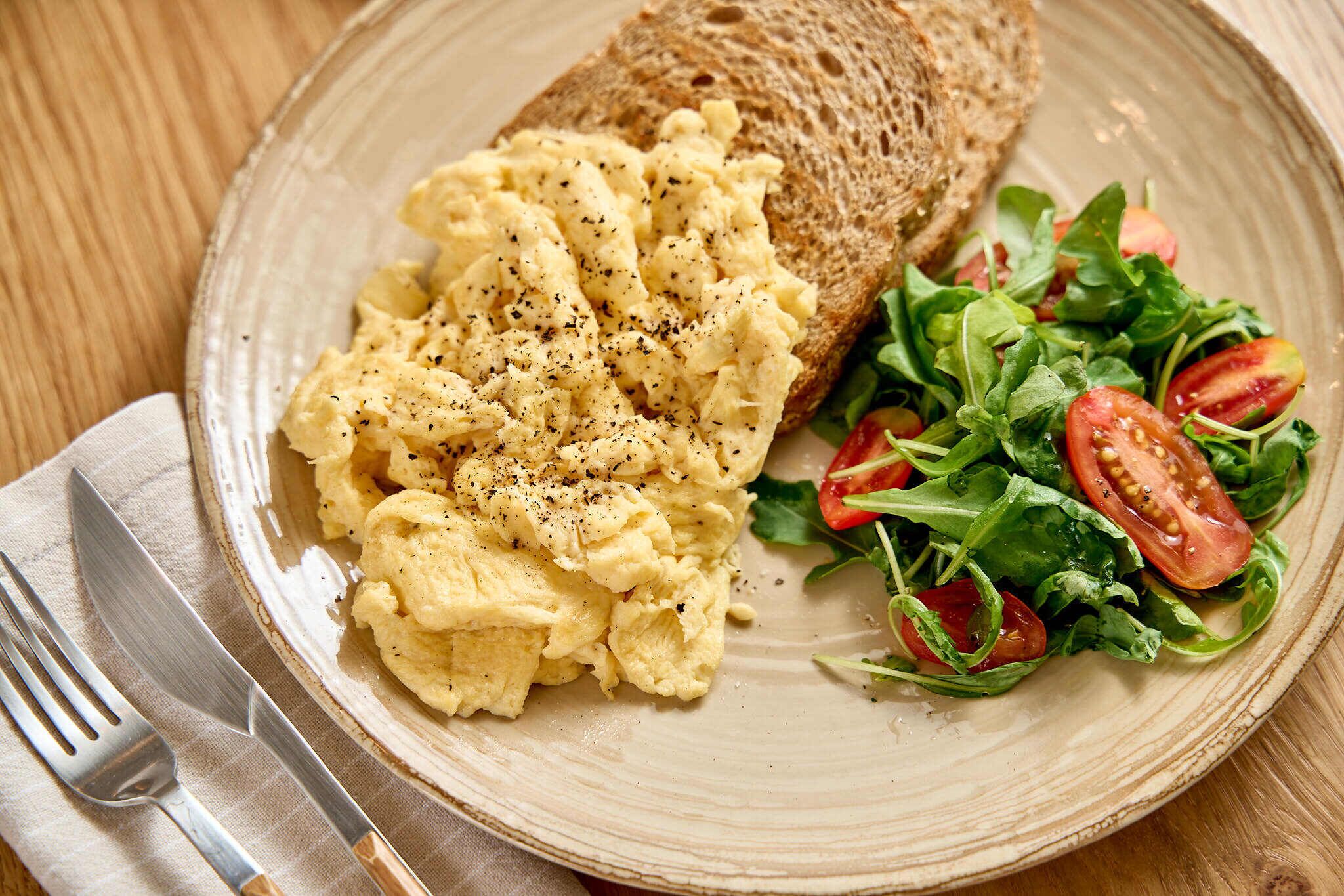 Scrambled eggs on toast with a side salad.