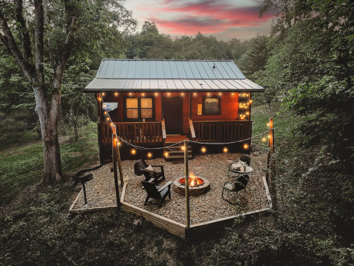 A cabin with a deck, outdoor seating, and a fire pit.
