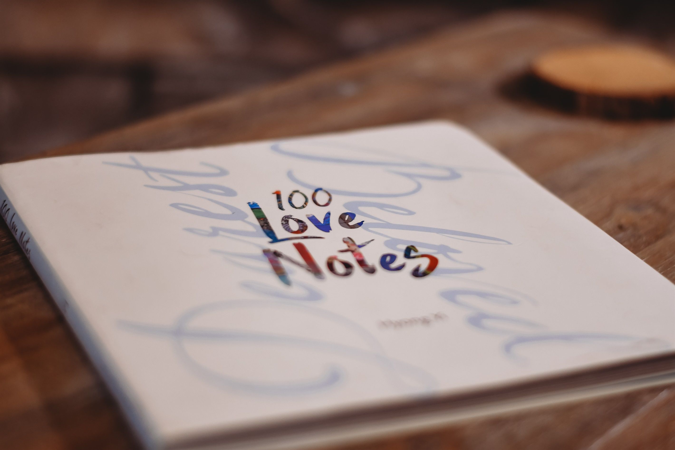 Un llibre anomenat '100 Love Notes' damunt una superfície de fusta.