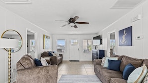 A living room with two sofas, a ceiling fan, and a large window.