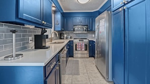 A kitchen with blue cabinets, stainless steel appliances, and a white countertop.
