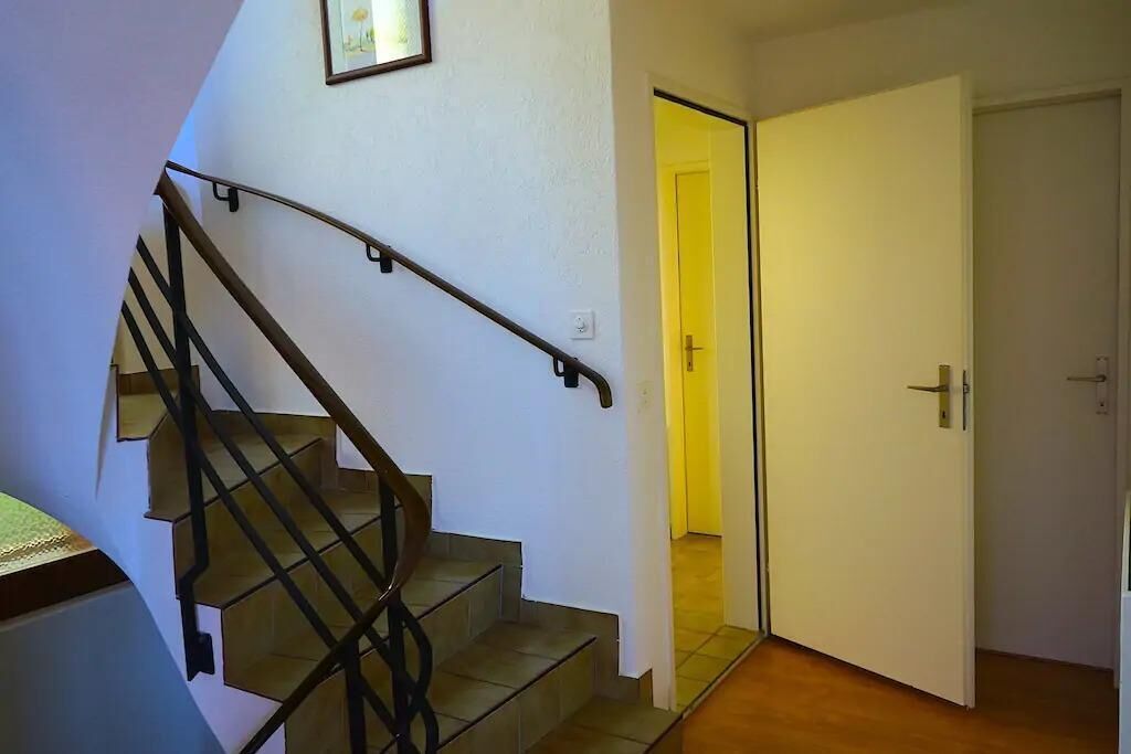 Escada com corrimão que leva a um quarto com porta fechada.