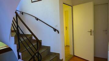 Escada com corrimão que leva a um quarto com porta fechada.
