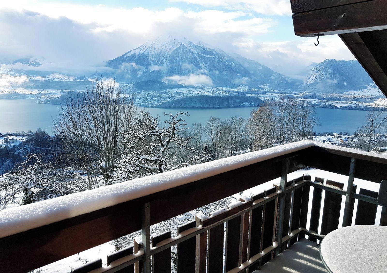 Un balcón con vistas a un paisaje nevado, un lago y una montaña.