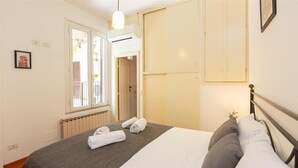 Et hotelværelse med seng, radiator, et vindue og en aircondition.