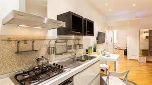 A modern kitchen with a gas stove, stainless steel sink, and black cabinets.