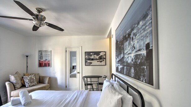 A hotel room with a bed, a ceiling fan, a sofa, a small table, and two framed pictures on the wall. - 313 Room with a view 1 block from the beach (Fort Lauderdale)