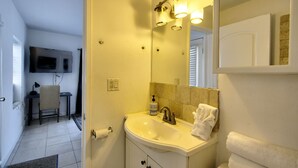 A bathroom with a sink, mirror, and towel rack. - 313 Room with a view 1 block from the beach (Fort Lauderdale)