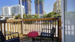 A wooden deck with two chairs and a small table, overlooking a parking lot and buildings under construction. - 313 Room with a view 1 block from the beach (Fort Lauderdale)