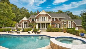 Une grande maison avec une piscine et des chaises longues.