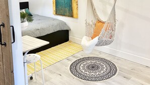 Ett mysigt rum med en hängstol, en säng, ett litet bord och en dekorativ matta.