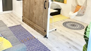 Ett modernt vardagsrum med en skjutdörr i stil med en lada, en hängmatta, en platt-TV och en köksdel.