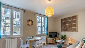 Ein gemütliches Wohnzimmer mit Essbereich, einem Fernseher und einem Wandbild.