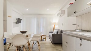 A modern kitchen with white cabinets, a grey sofa, and a dining area with white chairs and a table. - HotelZone L20 Beach Access (Cancún)