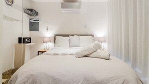 A neatly made bed with white linens, a bedside lamp, and a wall-mounted radio. - HotelZone L20 Beach Access (Cancún)