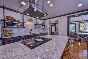 A modern kitchen with granite countertops, a central island, and built-in shelving.