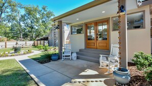 A house with a covered porch, a wooden door, and a small outdoor seating area with chairs and a table.