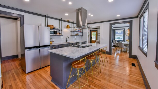 A modern kitchen with a central island, stainless steel appliances, and a bar area with stools.